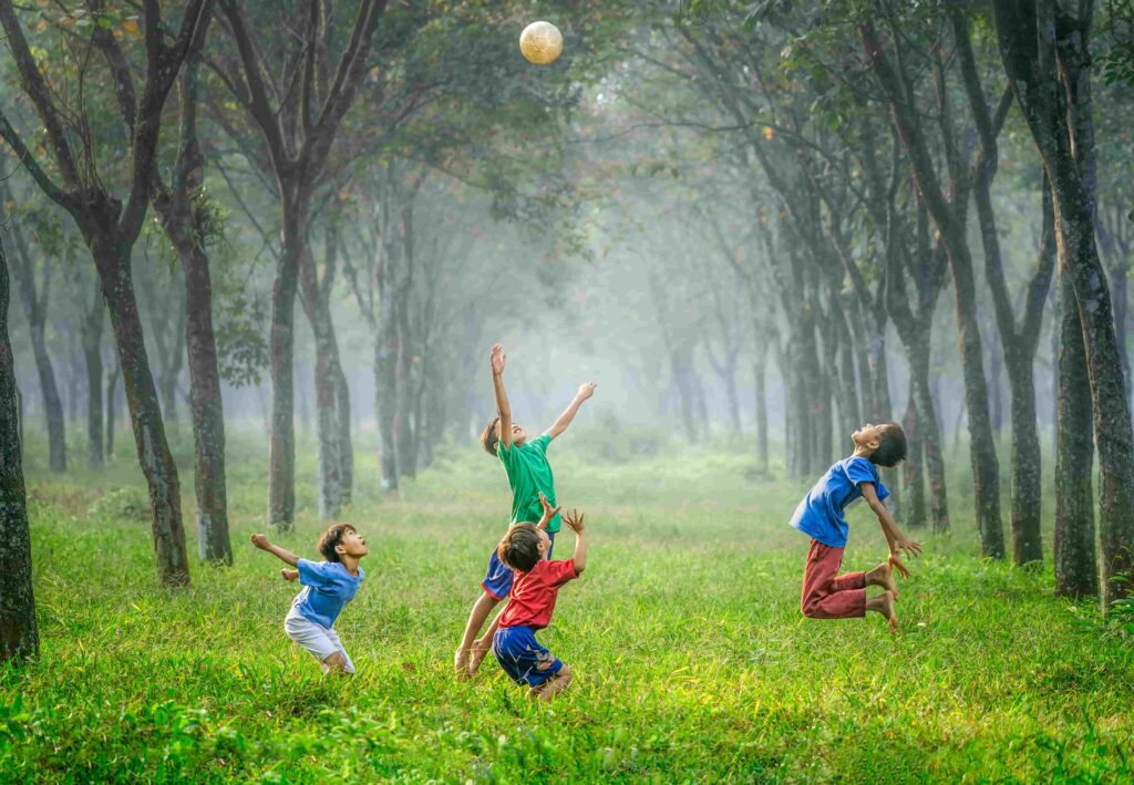 Four kids playing ball on the green grass.