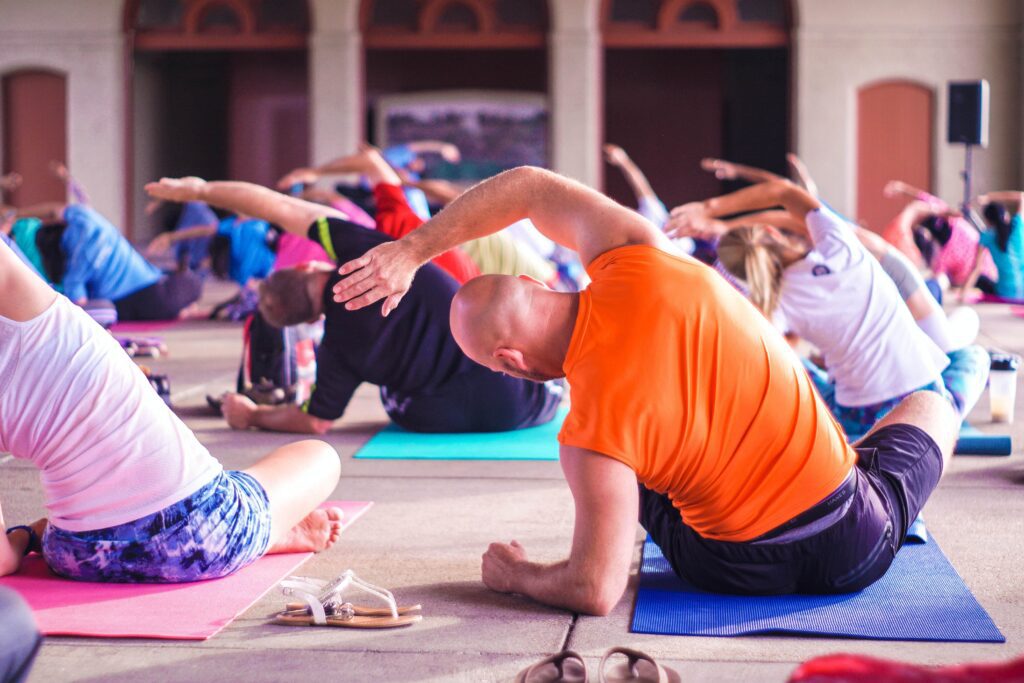 A yoga class with a group of people on mats, practicing various yoga positions.