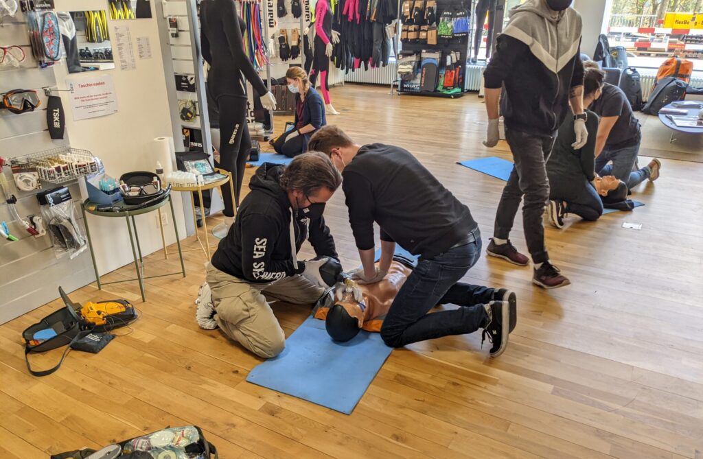 Two individuals practicing CPR on a training dummy during a first aid course.