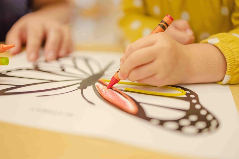 A child happily coloring with crayons, showcasing their creativity and imagination.