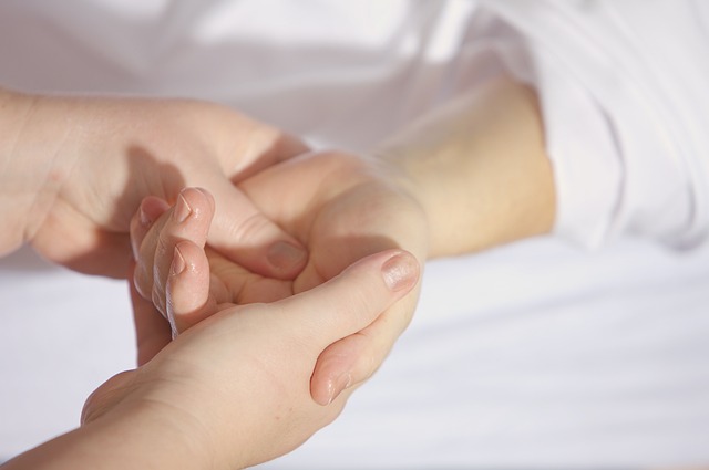 A person holding the hand of another person, symbolizing connection and support in Holistic Hands Therapy.