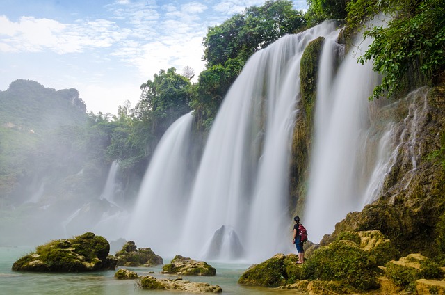 A person mesmerized by the breathtaking waterfall amidst the flowing river.