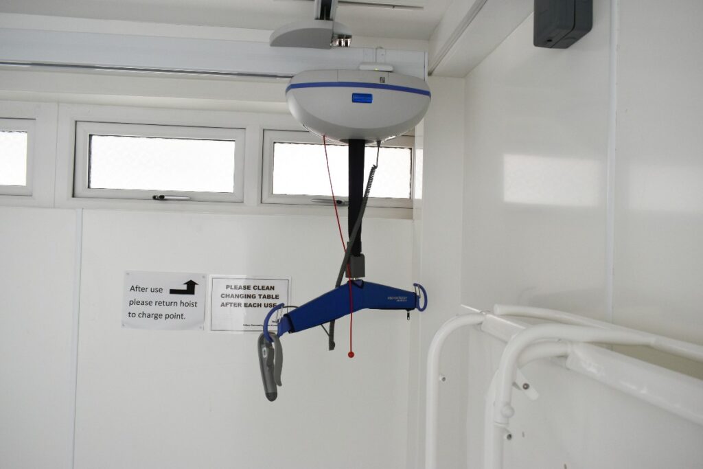 Ceiling hoist for disabled individuals, securely installed in the room's corner, providing efficient and safe transfer assistance.