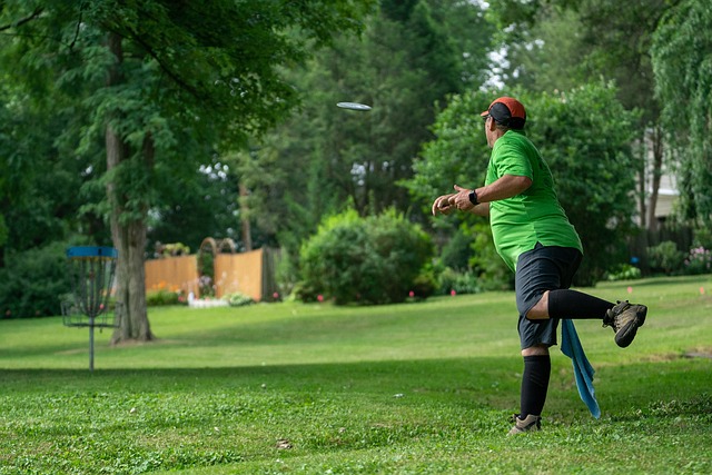 Man in green shirt reaching out to catch a frisbee in mid-air