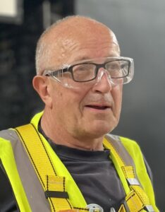 A man with safety glasses and a vest.