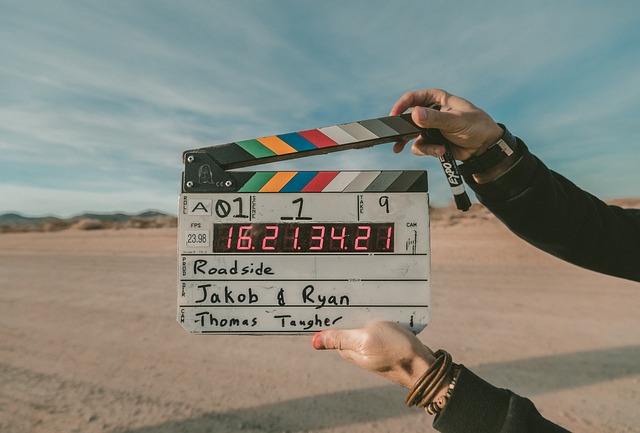 Person holding clapper board in desert, ready to film.