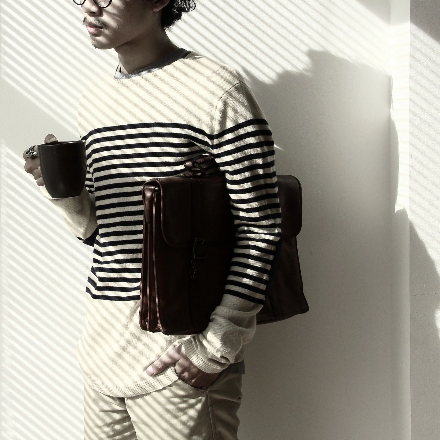 A young man with glasses, holding cup