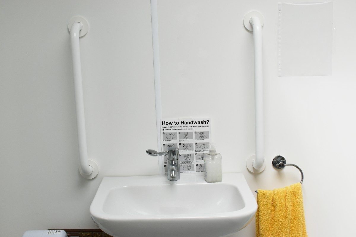 Image of a bathroom featuring a sink, towel rack, and holding bars on the wall