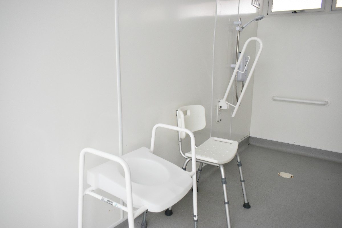 Accessible restroom featuring a toilet with grab bar, alongside additional seating options, ensuring comfort and convenience for individuals with disabilities.