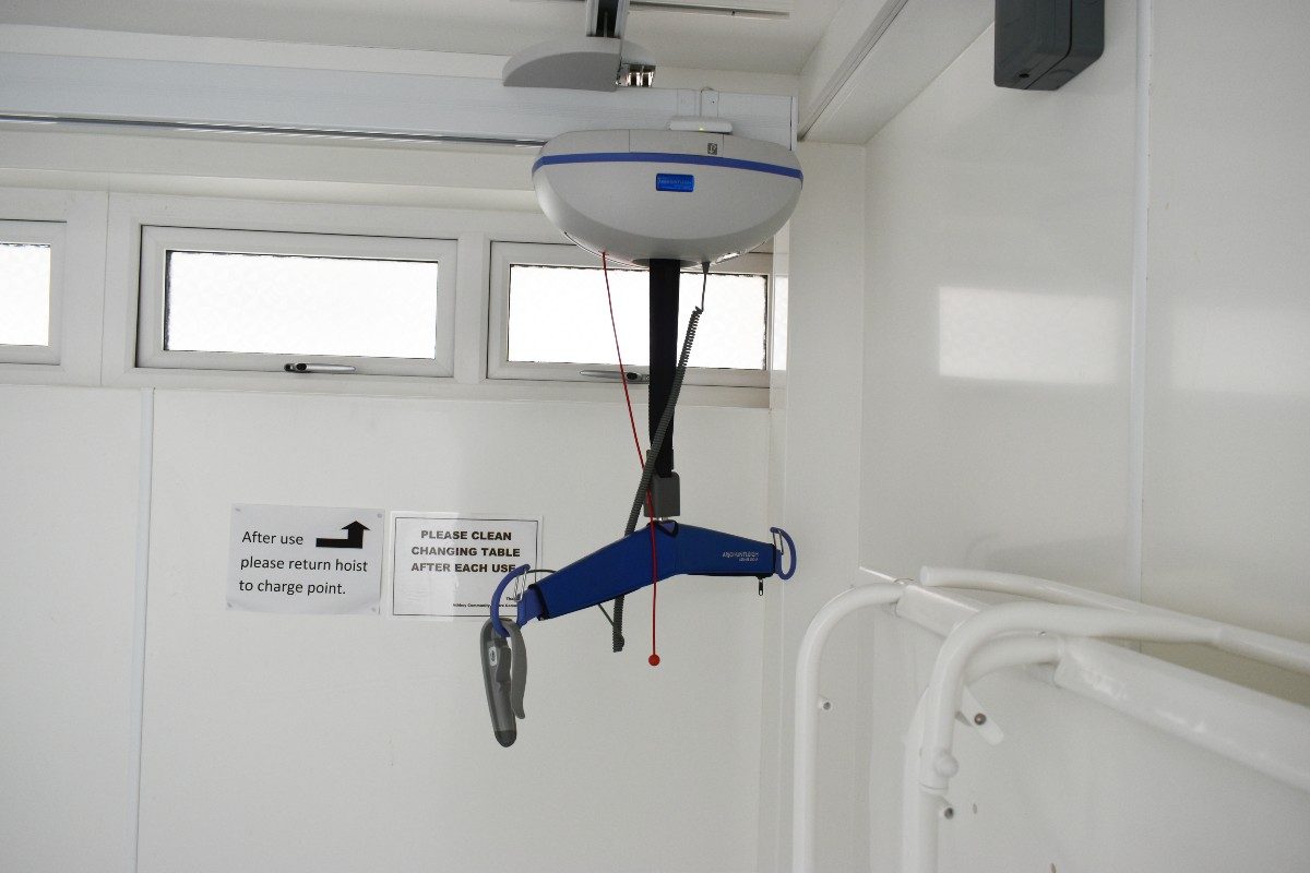 Ceiling hoist for disabled individuals, securely installed in the room's corner, providing efficient and safe transfer assistance.