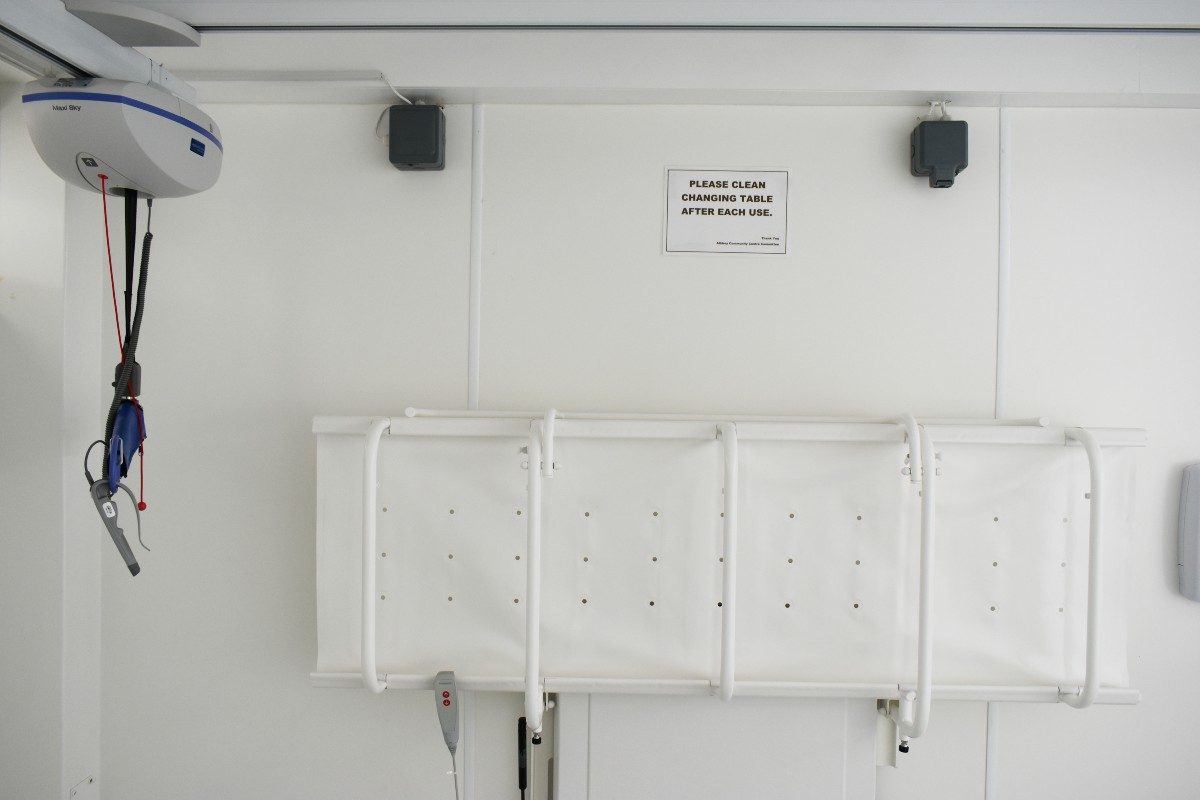 Ceiling hoist for disabled individuals, securely installed in the room's corner, providing efficient and safe transfer assistance.