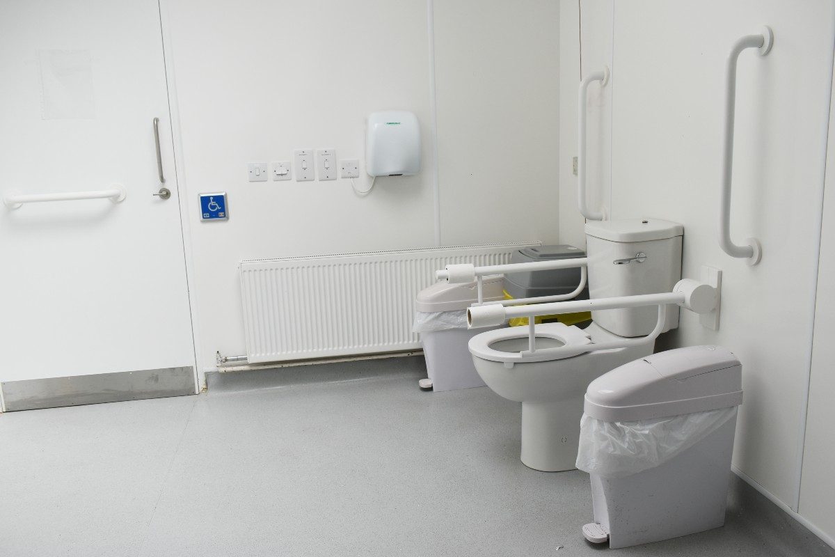 Accessible restroom featuring a toilet with grab bar, alongside additional seating options, ensuring comfort and convenience for individuals with disabilities.