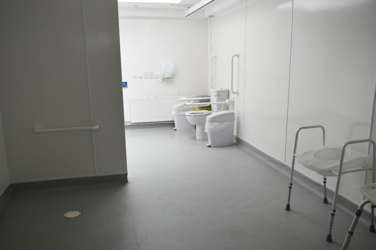 Accessible restroom featuring a toilet with grab bar, alongside additional seating options, ensuring comfort and convenience for individuals with disabilities.