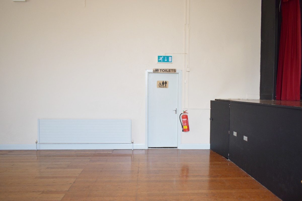 Wooden floor and door in room at St. James' Hall, entrance to toilets.