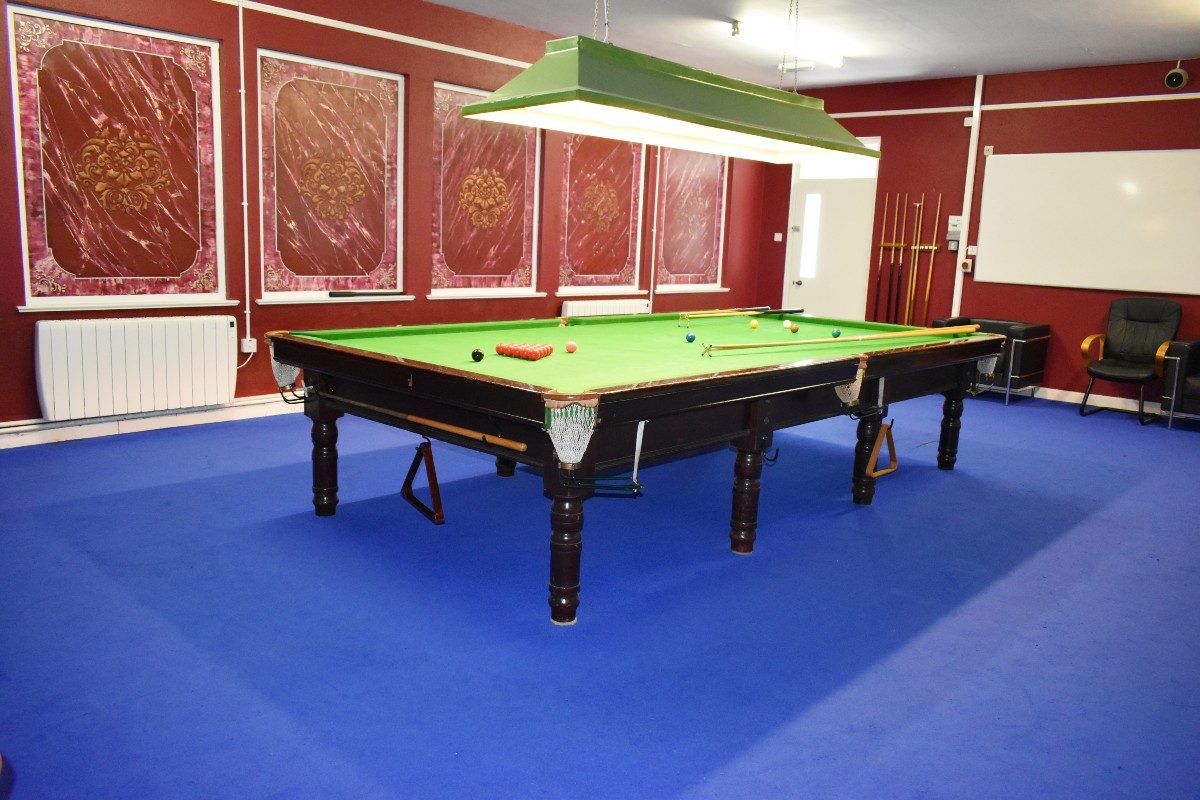 A snooker table in a room with red walls.