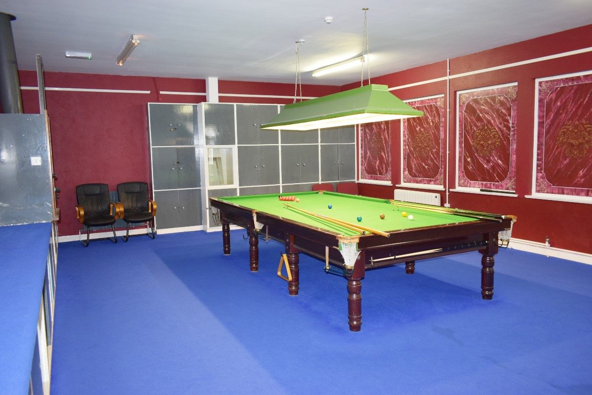 A snooker table in a room with red walls.