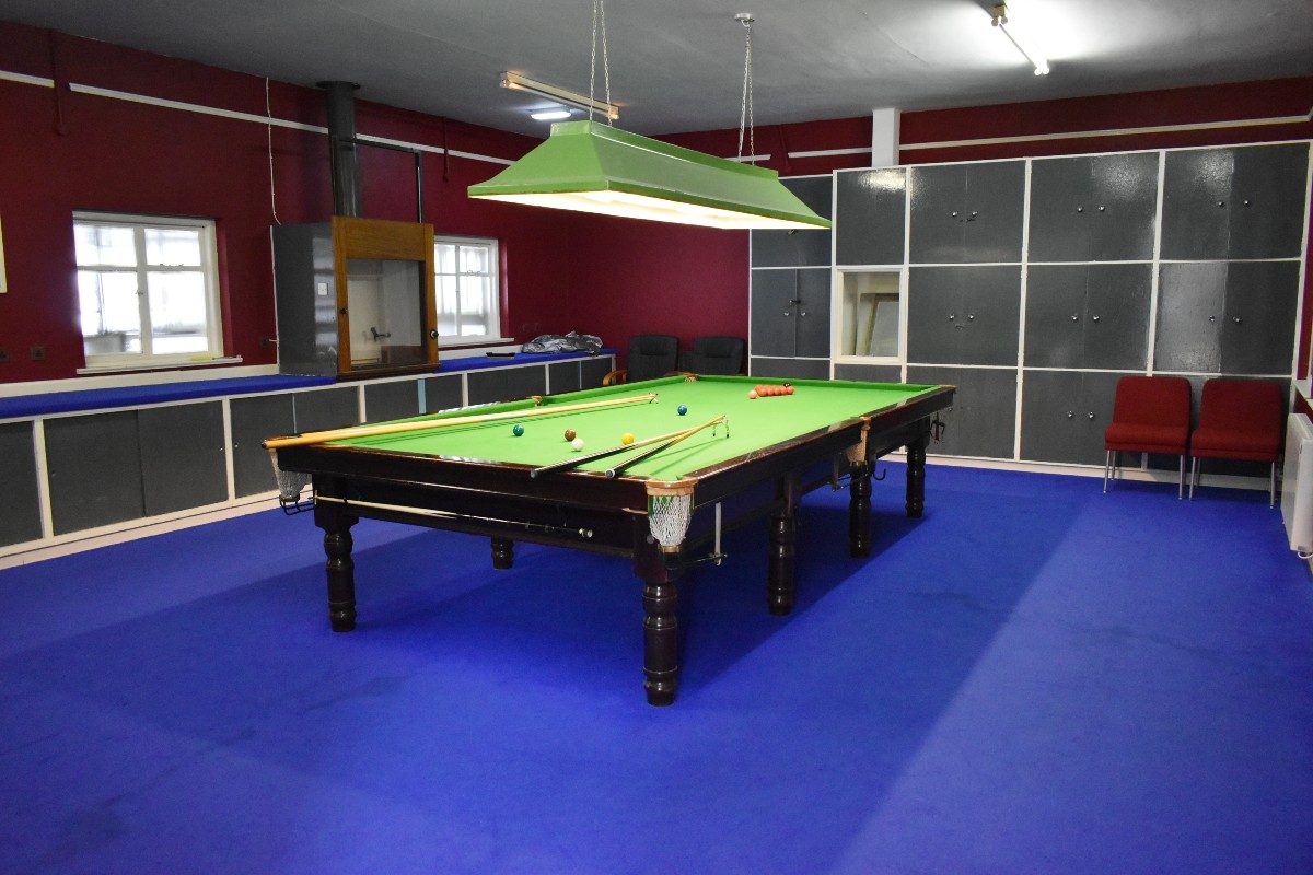 A snooker table in a room with red walls.