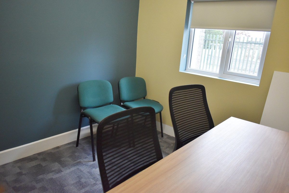 A desk and chair in a Zoom room with a flat screen TV.