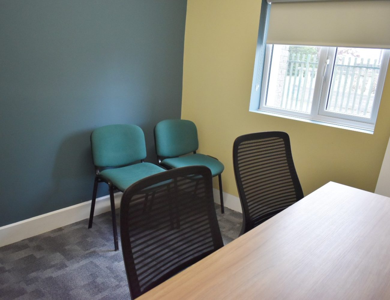 A desk and chair in a Zoom room with a flat screen TV.