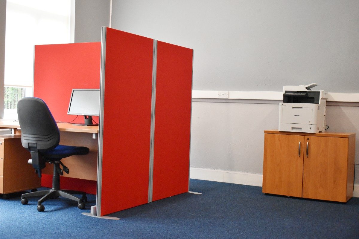 A hot desk in an office, printer on the background.