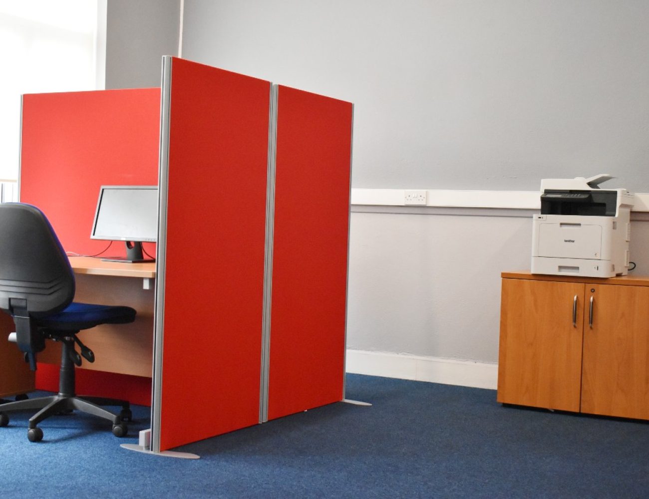 A hot desk in an office, printer on the background.