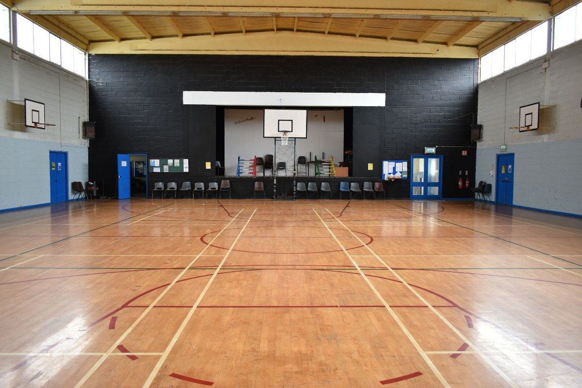 A wooden basketball court, with a stage on the background.