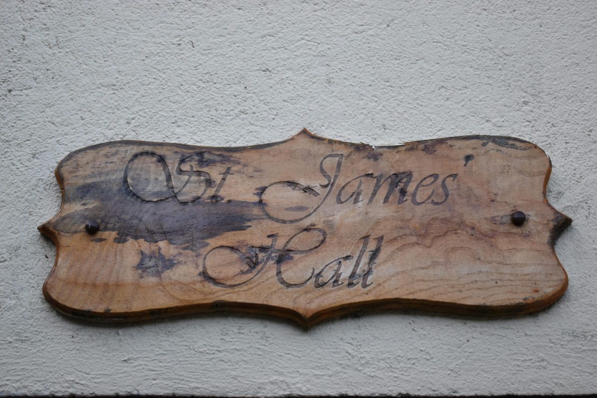 A wooden sign displaying 'St. James' Hall'.