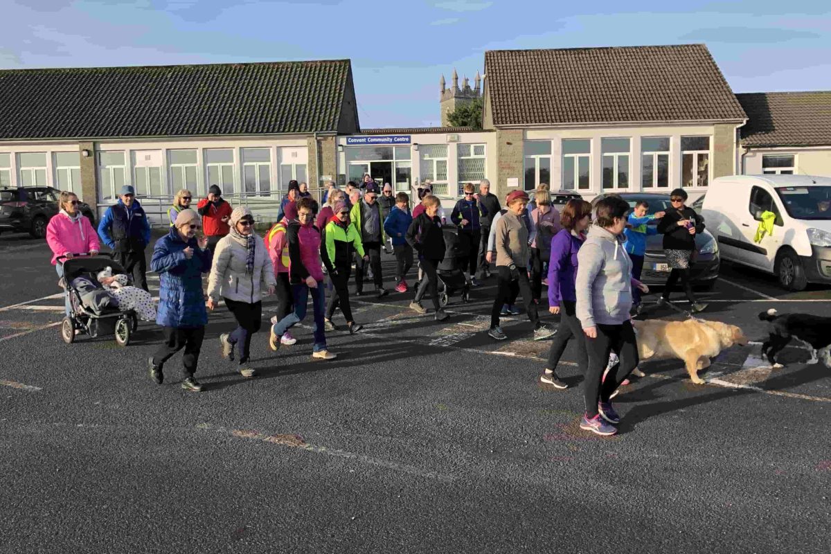 A group of people walking in a parking lot with Athboy Convent community Centre building in the background.