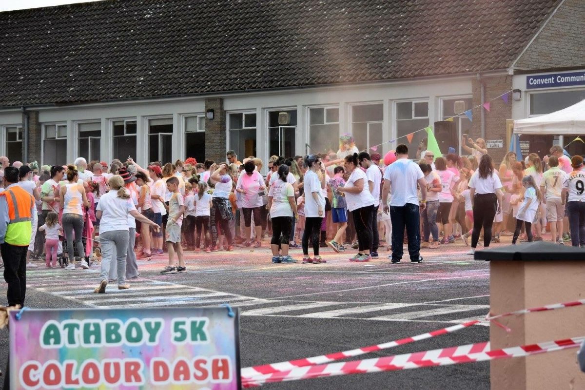 A diverse crowd gathers around a vibrant colored run, creating a lively atmosphere of excitement and anticipation.