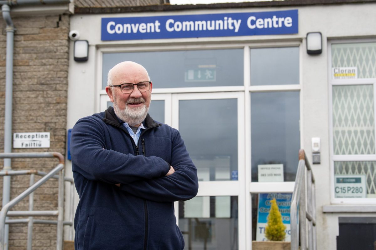 A man standing outside a community center, looking towards the camera.