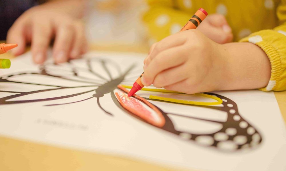 A child happily coloring with crayons, showcasing their creativity and imagination.