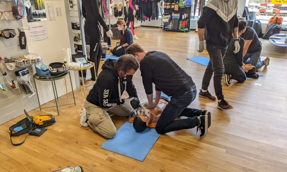 Two individuals practicing CPR on a training dummy during a first aid course.