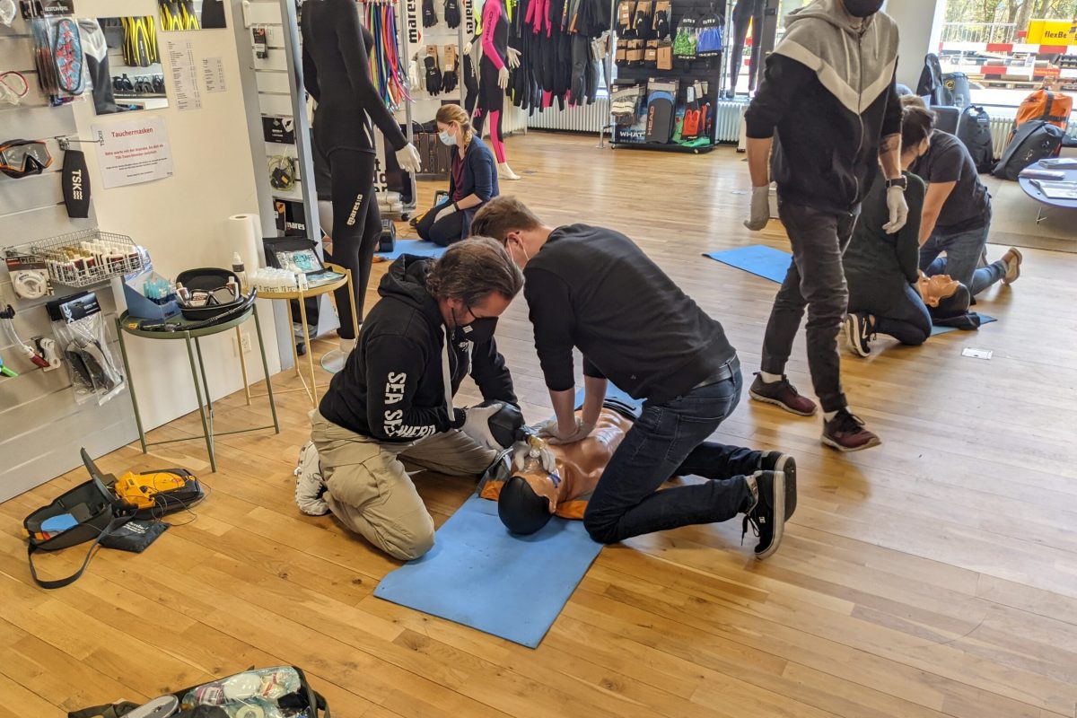 Two individuals practicing CPR on a training dummy during a first aid course.